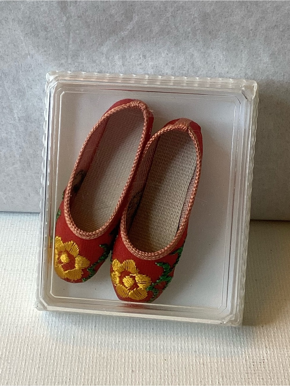 A pair of vintage red miniature slippers with large yellow embroidered flowers